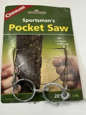 A 'Sportsman's Pocket Saw' in its retail packaging — a thin flexible wire saw with two finger rings, pictured cutting through a tree branch.